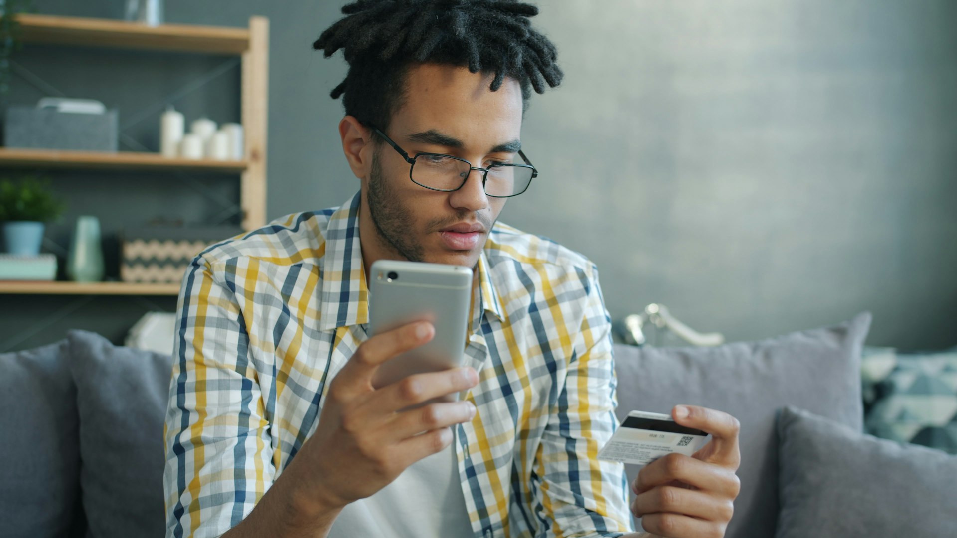 Man holding credit card and phone for online shopping.